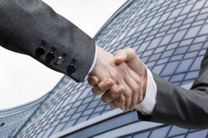 Two business men shaking hands in front of an all glass buliding