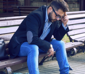 Business casual man sitting on a park bench looking frustrated