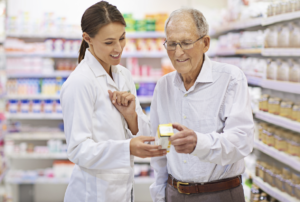 A woman pharmacist reading a prescription to an older gentlman